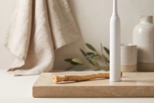 Miswak versus elektrische tandenborstel: natuurlijke siwak van Salvadora persica naast een elektrische tandenborstel op beige steen